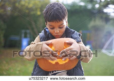 Stock Photo - Boy with pumpkin posing in garden. Fotosearch