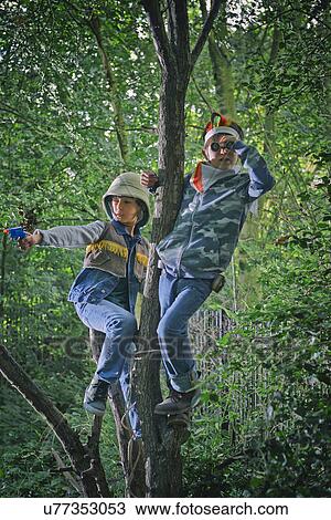 Stock Image - Boys dressed up looking out from forest trees. Fotosearch