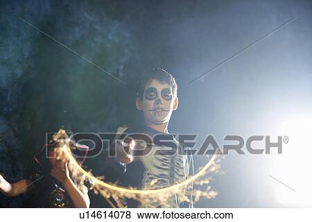 Stock Photo - Brother and sister wearing halloween costumes playing with sparklers in garden at night. Fotosearch