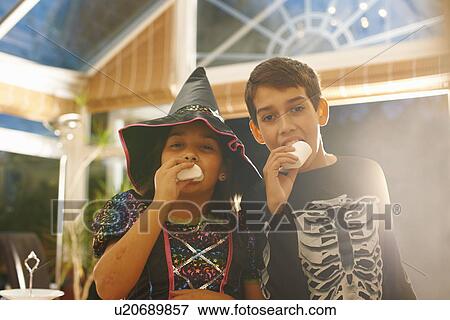 Brother and sister wearing halloween costumes eating marshmallows View Large Photo Image Stock Photo - Brother and sister wearing halloween costumes eating marshmallows. Fotosearch