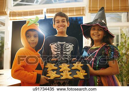 Brothers and sister wearing halloween costumes holding tray of gingerbread men View Large Photo Image Stock Photography - Brothers and sister wearing halloween costumes holding tray of gingerbread men. Fotosearch