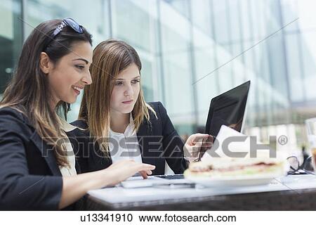 Businesswomen using laptop on working lunch View Large Photo Image Stock Image - Businesswomen using laptop on working lunch. Fotosearch