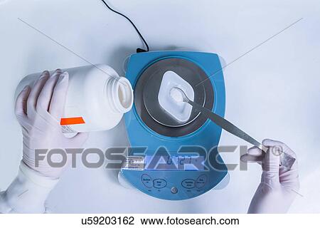 Stock Image - "Cancer research laboratory, hands of female scientist weighing chemicals". Fotosearch