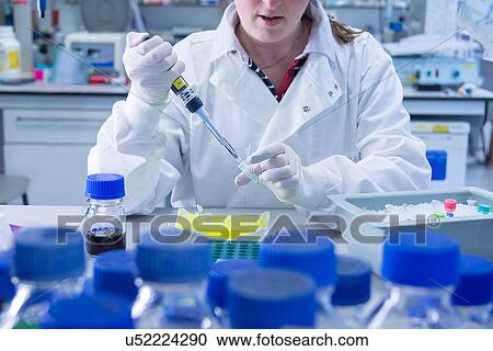 Stock Image - "Cancer research laboratory, scientist working with cells kept in ice after storage in sub zero temperatures in a liquid nitrogen cryopreservation chamber". Fotosearch