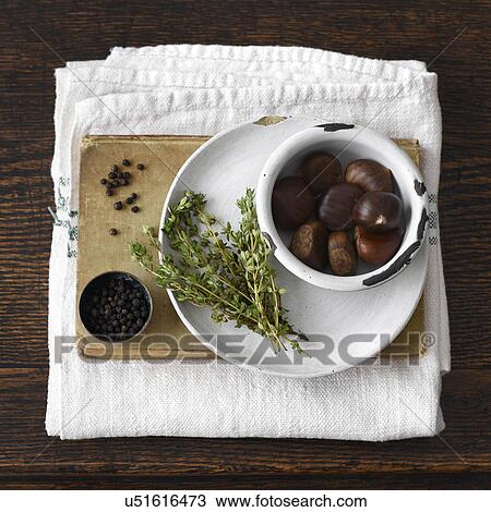 Stock Image - "Chestnuts, plate, thyme, book, black pepper, kitchen towel". Fotosearch