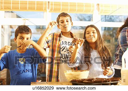 Stock Photo - Children tasting cake mixture in kitchen. Fotosearch