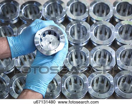 Stock Image - Close up of hands holding parts on production line in factory. Fotosearch