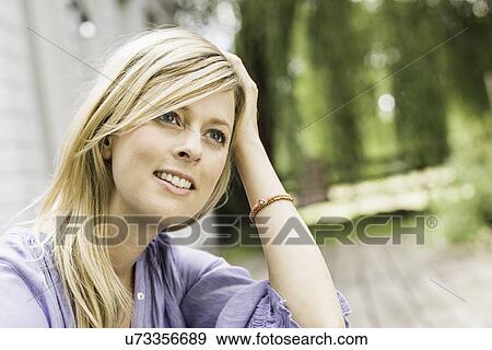 Stock Photo - Close up portrait of mid adult woman sitting in garden. Fotosearch