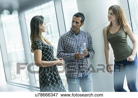 Stock Photo - Colleagues having discussion in corridor. Fotosearch
