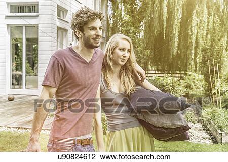 Couple carrying cushions in garden View Large Photo Image Stock Image - Couple carrying cushions in garden. Fotosearch