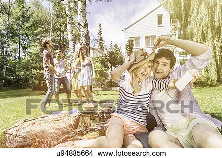 Picture - Couple taking selfie on picnic blanket. Fotosearch