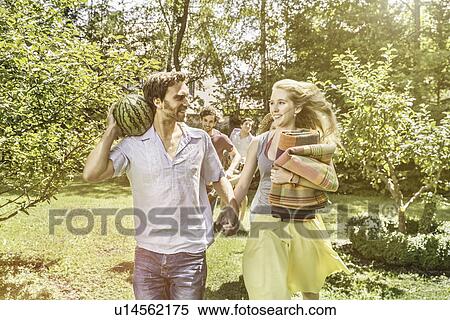 Couple walking in garden preparing for picnic View Large Photo Image Stock Photography - Couple walking in garden preparing for picnic. Fotosearch