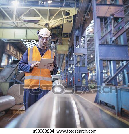 Picture - Engineer checking steel part with digital tablet in engineering factory. Fotosearch