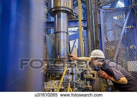 Stock Photography - Engineer heat treating steel parts in induction furnace in engineering factory. Fotosearch