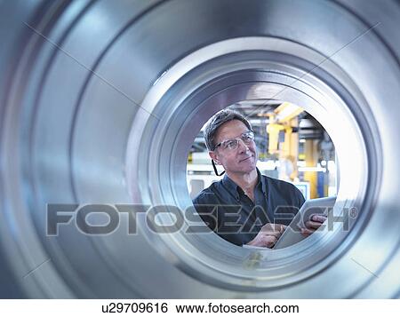 Stock Photograph - Engineer inspecting finished parts in factory. Fotosearch