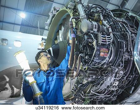 Engineer inspecting jet engine in aircraft maintenance factory View Large Photo Image Stock Photograph - Engineer inspecting jet engine in aircraft maintenance factory. Fotosearch