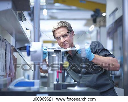 Stock Image - Engineer inspecting part at work station in engineering factory. Fotosearch