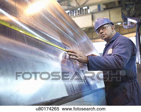 Stock Photography - Engineer setting up specialist lathe in steel engineering factory. Fotosearch
