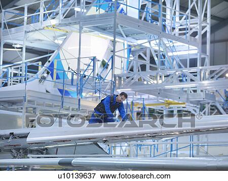 Stock Photo - Engineer working on aircraft wing in aircraft maintenance factory. Fotosearch