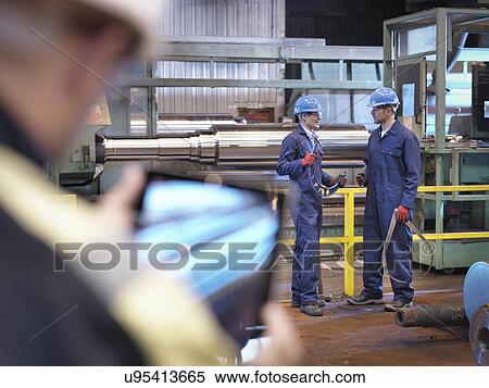 Stock Photography - Engineers at lathe in engineering factory. Fotosearch