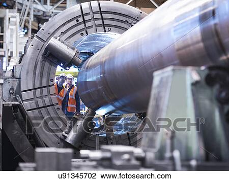 Stock Image - Engineers checking steel part in engineering factory. Fotosearch