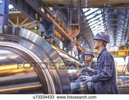 Stock Image - Engineers using ultrasound to check steel part in engineering factory. Fotosearch