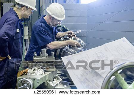 Engineers working on lathe with drawings View Large Photo Image Stock Image - Engineers working on lathe with drawings. Fotosearch