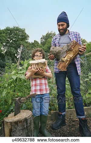Stock Photo - Father and son with chop logs on allotment. Fotosearch
