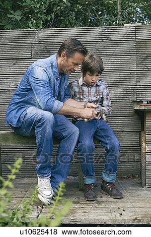 Father showing son how to use pocket knife on allotment View Large Photo Image Stock Photo - Father showing son how to use pocket knife on allotment. Fotosearch