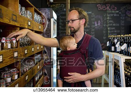 Father with baby daughter looking at jars in shop View Large Photo Image Picture - Father with baby daughter looking at jars in shop. Fotosearch