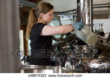 Stock Image - Female brewer working in brewhouse. Fotosearch