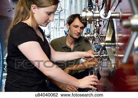 Stock Image - Female brewer working in brewhouse. Fotosearch
