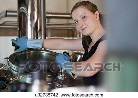 Stock Image - Female brewer working in brewhouse. Fotosearch