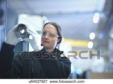 Stock Photo - Female engineer inspecting part in factory. Fotosearch