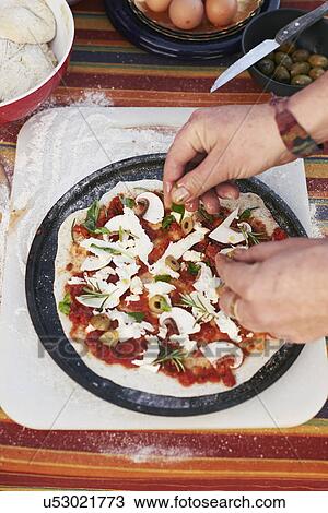 Stock Image - Female hands preparing pizza on garden table. Fotosearch