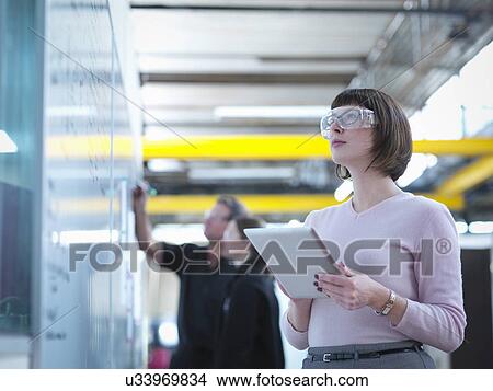 Female worker using digital tablet in factory View Large Photo Image Picture - Female worker using digital tablet in factory. Fotosearch