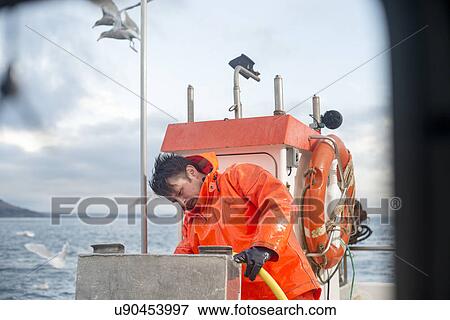 Fisherman cleaning fishing boat View Large Photo Image Stock Photo - Fisherman cleaning fishing boat. Fotosearch