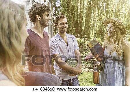 Stock Image - Friends in garden preparing for picnic. Fotosearch