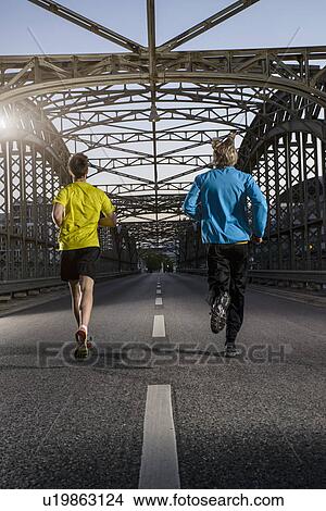 "Friends jogging on bridge, Munich, Bavaria, Germany" View Large Photo Image Picture - "Friends jogging on bridge, Munich, Bavaria, Germany". Fotosearch