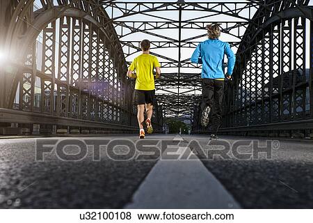 Stock Photo - "Friends jogging on bridge, Munich, Bavaria, Germany". Fotosearch