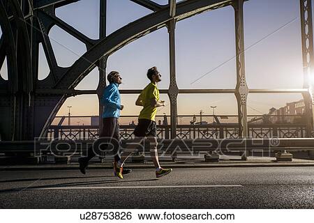 Stock Photograph - "Friends jogging on bridge, Munich, Bavaria, Germany". Fotosearch