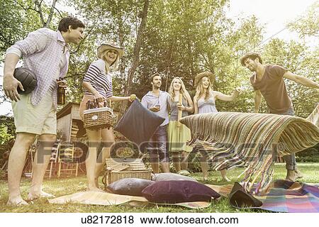 Stock Photo - Friends preparing for picnic in garden. Fotosearch