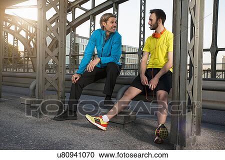 Stock Image - "Friends relaxing on bridge, Munich, Bavaria, Germany". Fotosearch