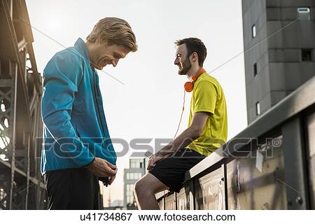 Stock Photo - "Friends taking break on bridge, Munich, Bavaria, Germany". Fotosearch