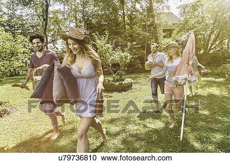 Friends walking in garden preparing for picnic View Large Photo Image Stock Image - Friends walking in garden preparing for picnic. Fotosearch