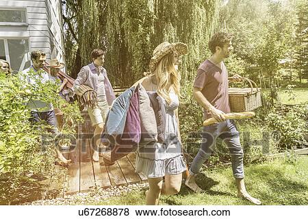 Friends walking in garden preparing for picnic View Large Photo Image Stock Photo - Friends walking in garden preparing for picnic. Fotosearch
