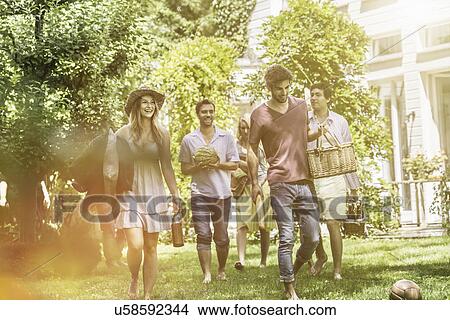 Picture - Friends walking in garden with picnic. Fotosearch