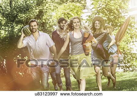 Friends walking in garden with picnic View Large Photo Image Stock Photo - Friends walking in garden with picnic. Fotosearch