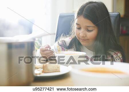 Girl eating bowl of soup in kitchen View Large Photo Image Stock Image - Girl eating bowl of soup in kitchen. Fotosearch