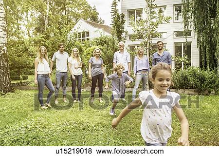 Girl in garden with family in background View Large Photo Image Stock Photo - Girl in garden with family in background. Fotosearch